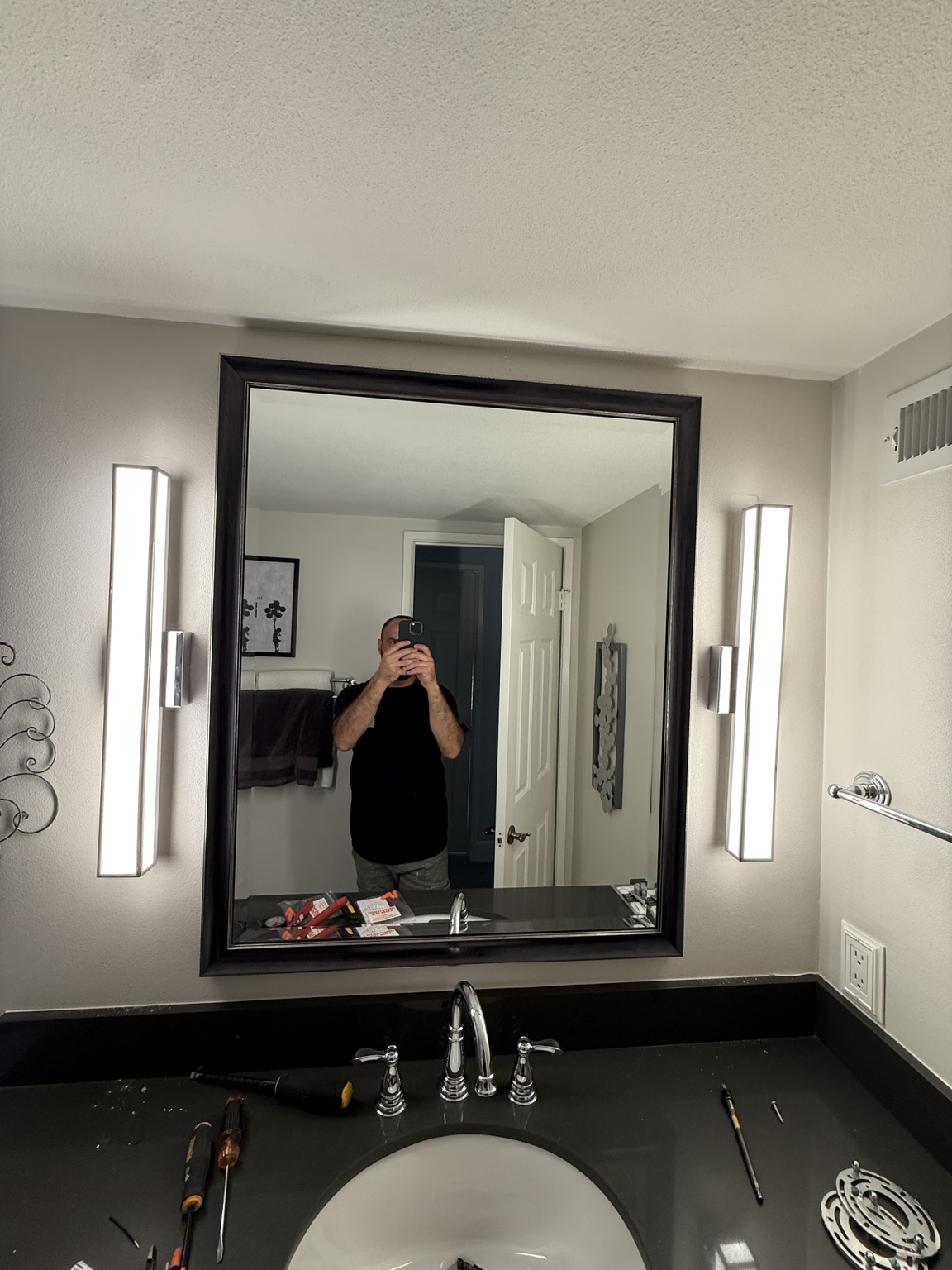 Modern vertical vanity lights installed beside a bathroom mirror